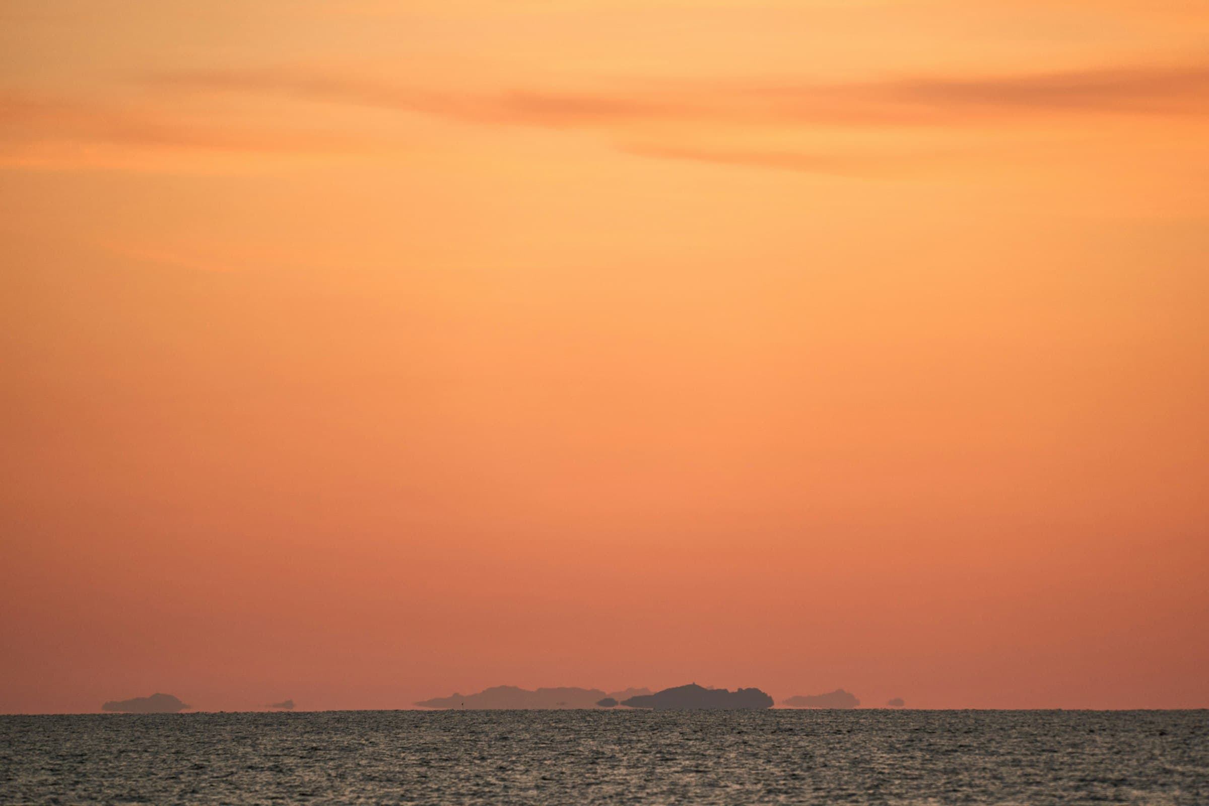 Golden sunset over a calm Mediterranean sea with distant islands on the horizon