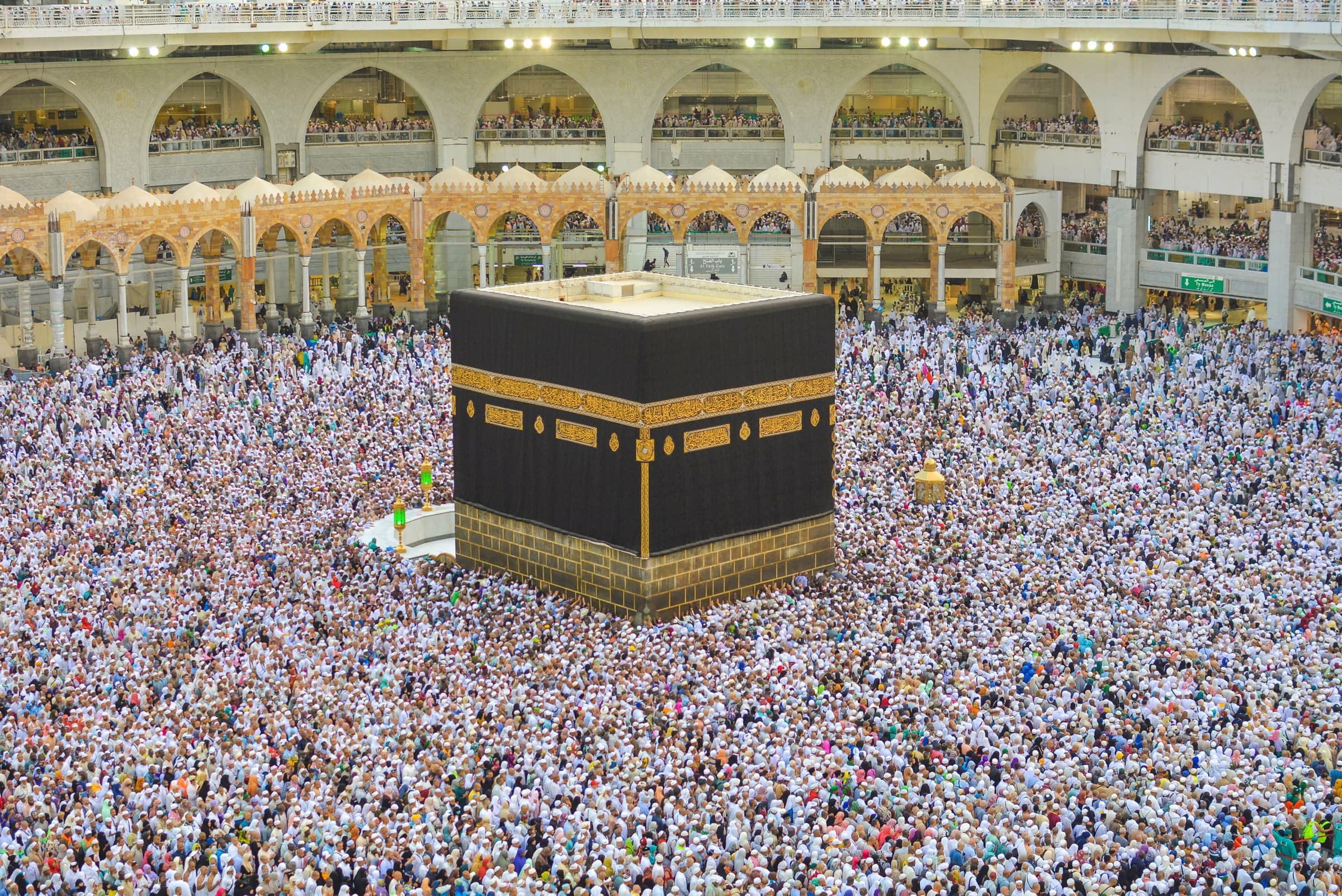 Pilgrims in white circling the Kaaba in the courtyard of Masjid al-Haram in daylight